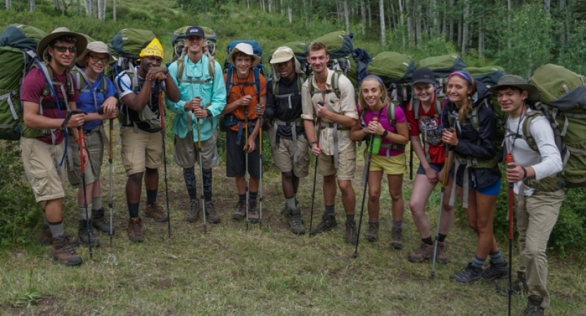 A group of outward bound gap year students wearing backpacks pose for a photo 